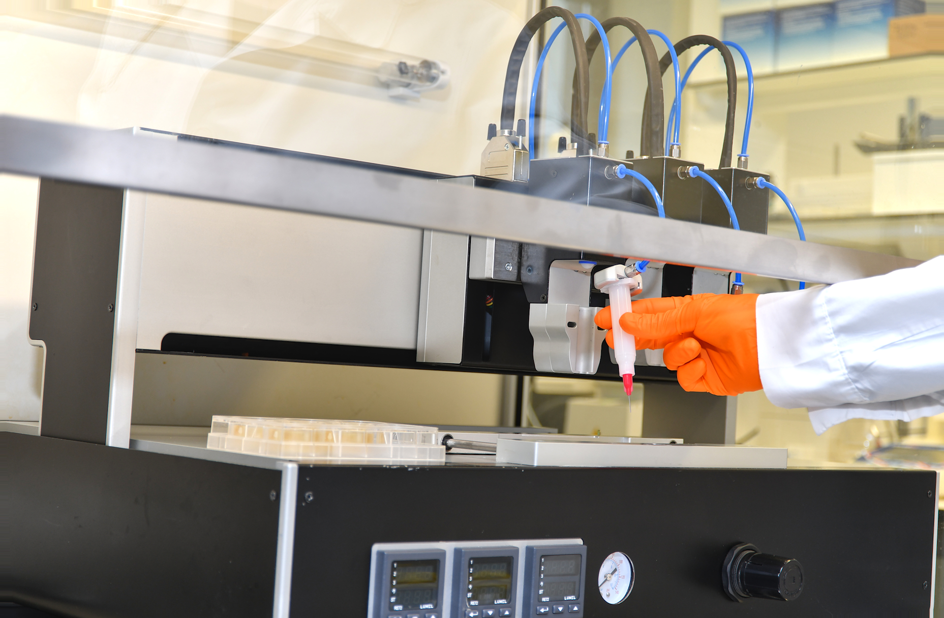 Odmerjanje tekočine s pipeto v laboratorijski komori nad ploščo z vzorci.