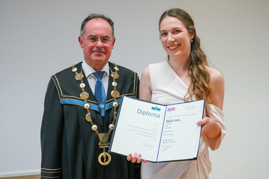 Diplomantka v svetli obleki z dekanom in diplomo. Podelitev diplom Medicinske fakultete UM, 15. junija 2023.