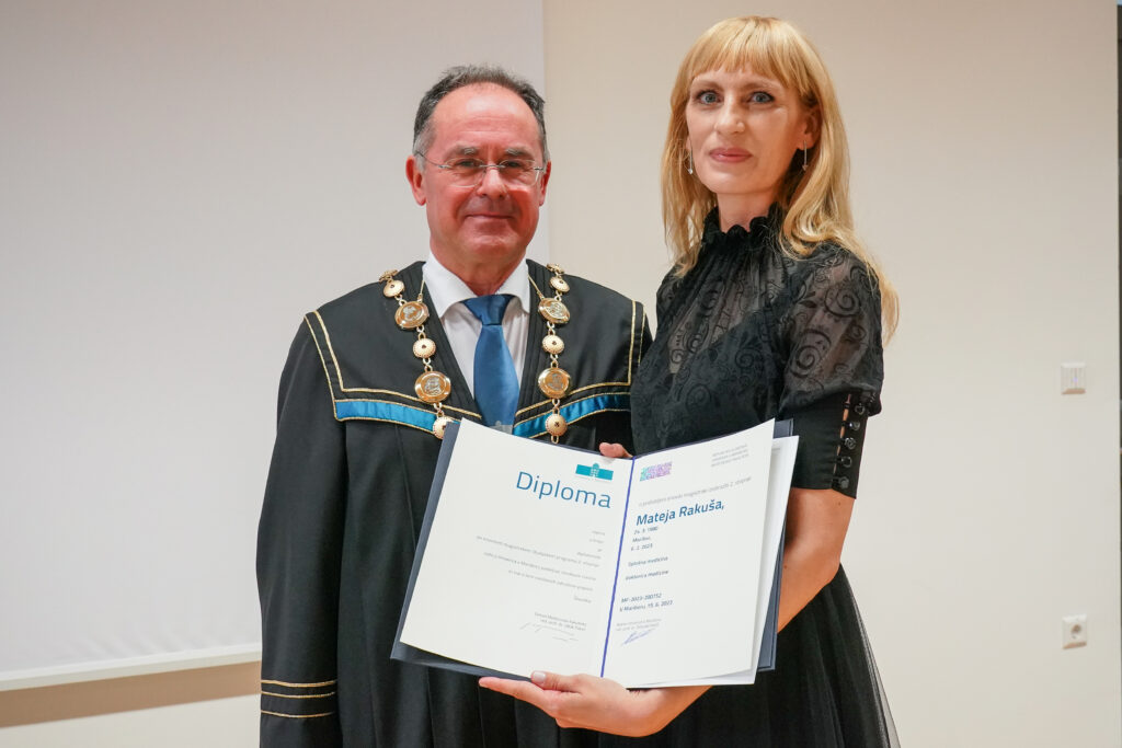 Diplomantka v črni obleki z dekanom in diplomo. Podelitev diplom Medicinske fakultete UM, 15. junija 2023.