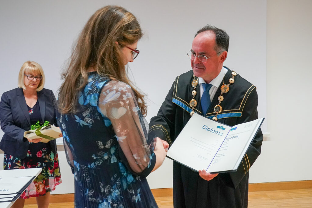 Dekan predaja diplomo diplomantki v modri obleki. Podelitev diplom Medicinske fakultete UM, 15. junija 2023.