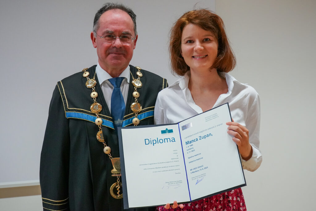 Diplomantka v beli bluzi z dekanom in diplomo. Podelitev diplom Medicinske fakultete UM, 15. junija 2023.