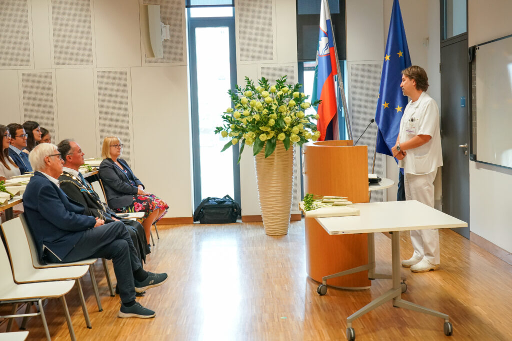 Govorec v beli obleki nagovarja goste v predavalnici. Podelitev diplom Medicinske fakultete UM, 15. junija 2023.