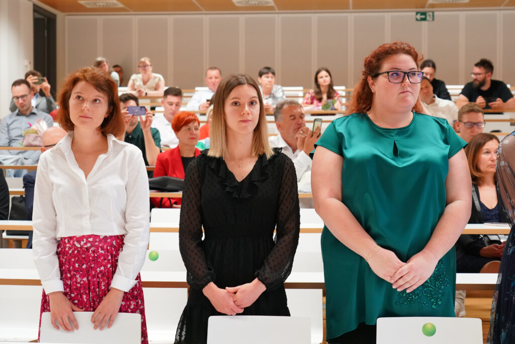 Tri diplomantke stojijo pred svojimi sedeži. Podelitev diplom Medicinske fakultete UM, 15. junija 2023.
