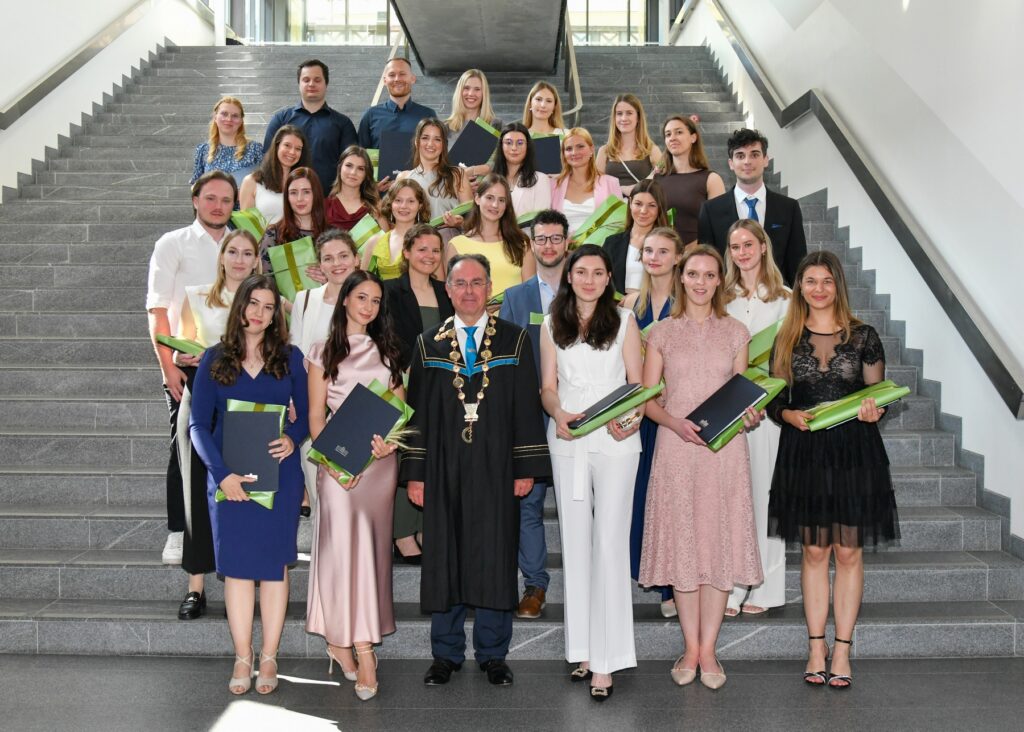 Absolventinnen und Absolventen und der Dekan auf einem Gruppenfoto auf der Treppe. Diplomverleihung der MF UM 2025.